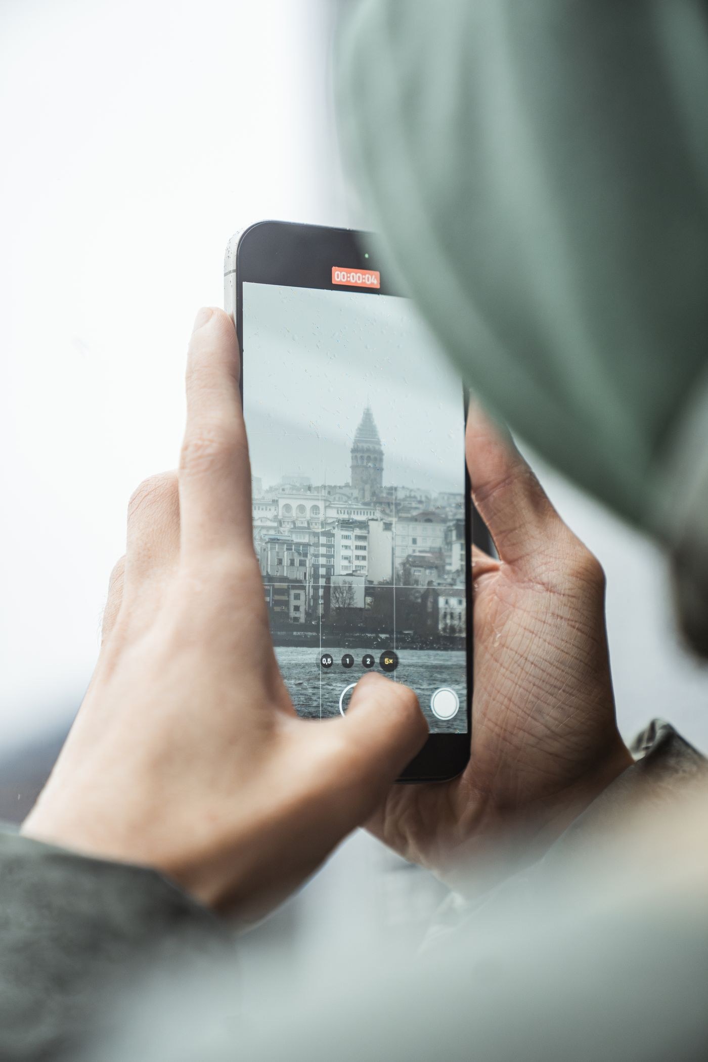 Hände beim Fotografieren eines Turms mit dem Smartphone