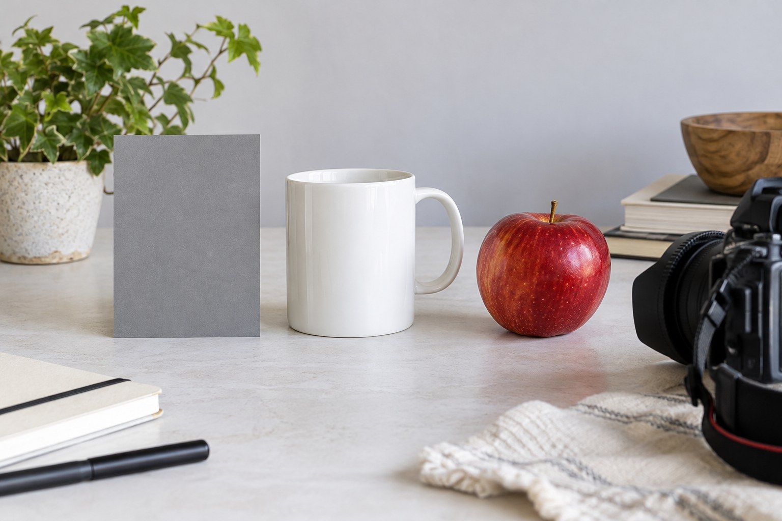 Graue Referenzkarte neben weißer Tasse und rotem Apfel
